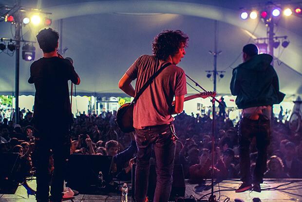 student band performing on stage in tent with crowd