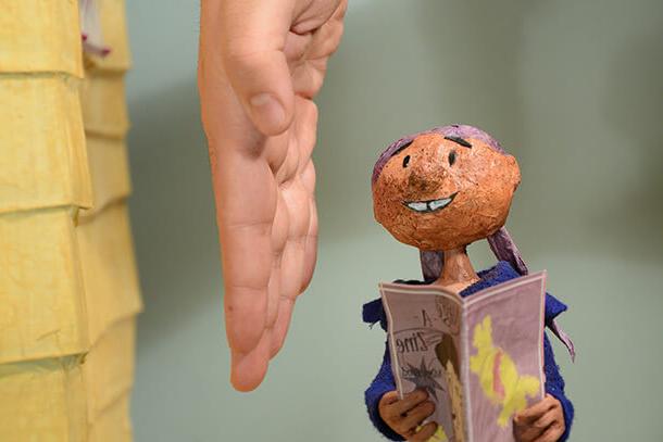 clay character used in animation projects with person's hand