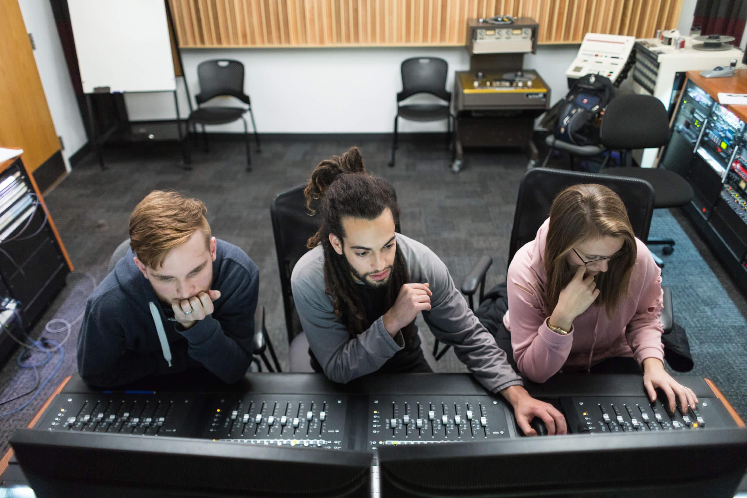 音频艺术和声学专业的学生在录音棚的声板前