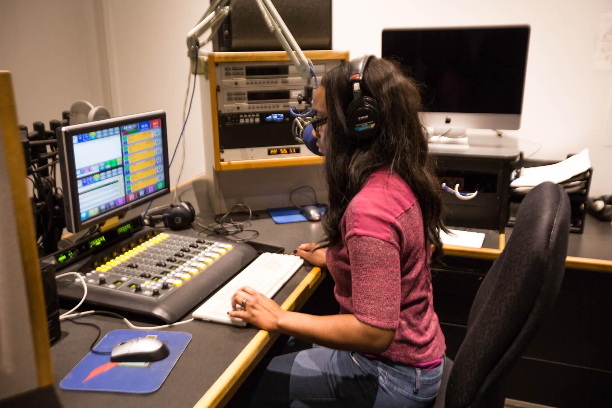 person sitting at controls in radio station