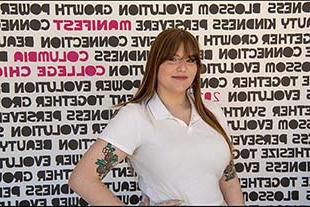 Miranda Prater posing in front of signage created for Columbia's annual 清单 celebration; sign includes unique font with words such as "Connection" "Kindness," and "Growth."